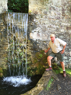 DL Koontz husband, Joe, beside one of the Bedford Springs, cascading through a rock wall into a pool