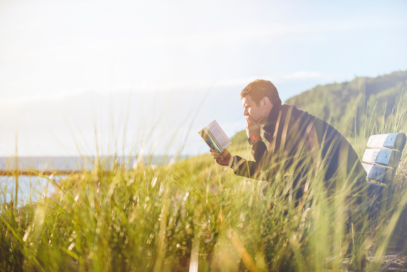 12 Ways to Add More Joy to Your Book-Reading Bliss, man reading on bench overlooking large lake
